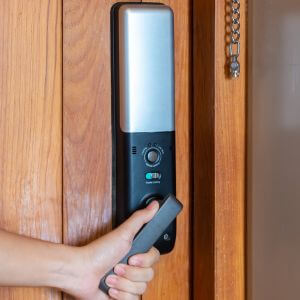hombre sostiene la manija de una cerradura de puerta digital inteligente mientras abre o cierra la puerta.