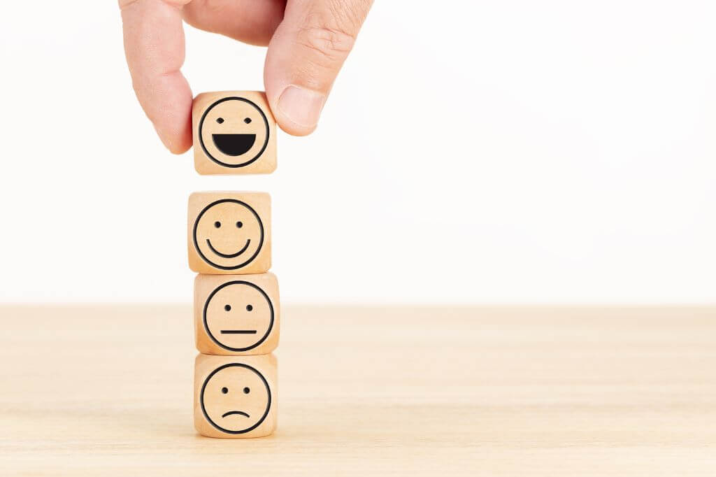 Concepto de encuesta de evaluación y satisfacción del servicio al cliente Escogió a mano el emoticón de la cara feliz en bloques de madera.
